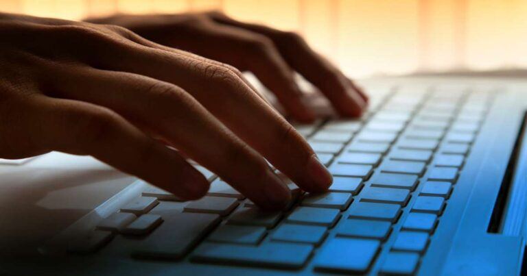 close up of hands typing on a keyboard