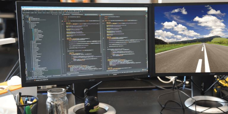 desktop application screen next to a monitor showing an open highway