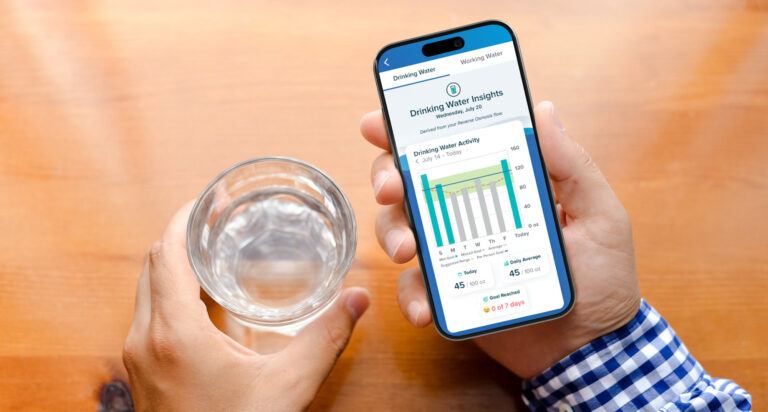 man holding a glass of water and looking at water insights on his phone app