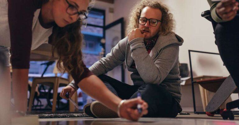 tech team collaborating in planning session on the floor with a marker