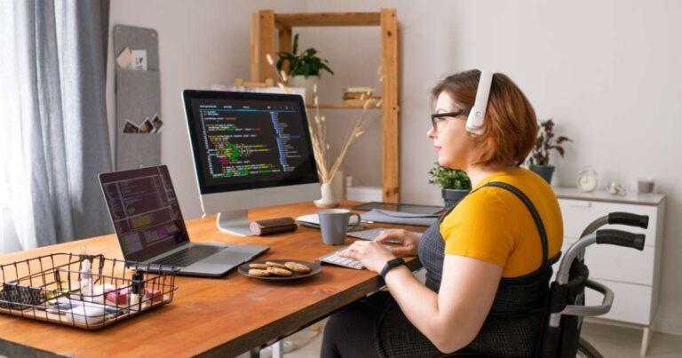 programmer at computer with dual monitors working on coding project while wearing headphones