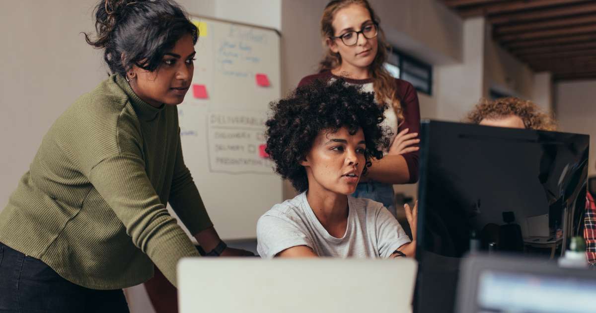 group of designers and engineers collaborating over a screen at one person's desk