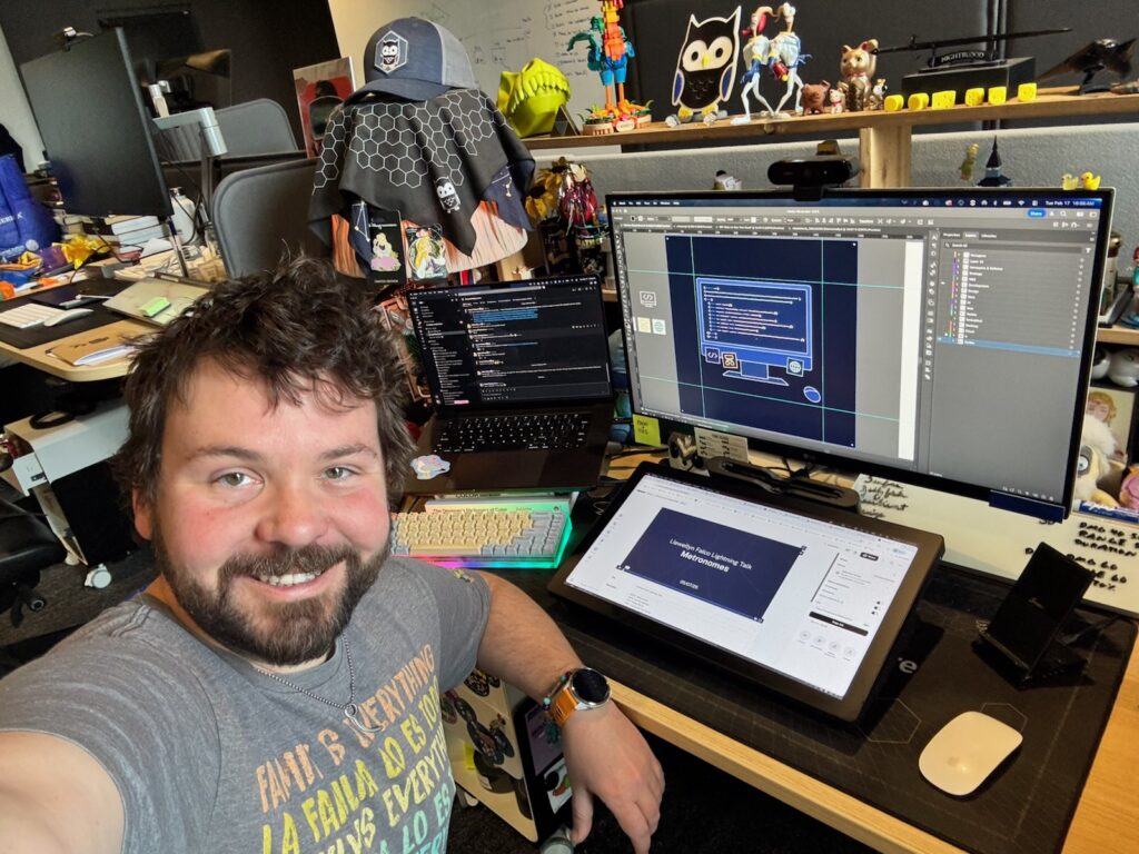 Adam Sturm, Marketing Graphic Designer at SEP, sitting at his desk and smiling at the camera. It's a selfie!