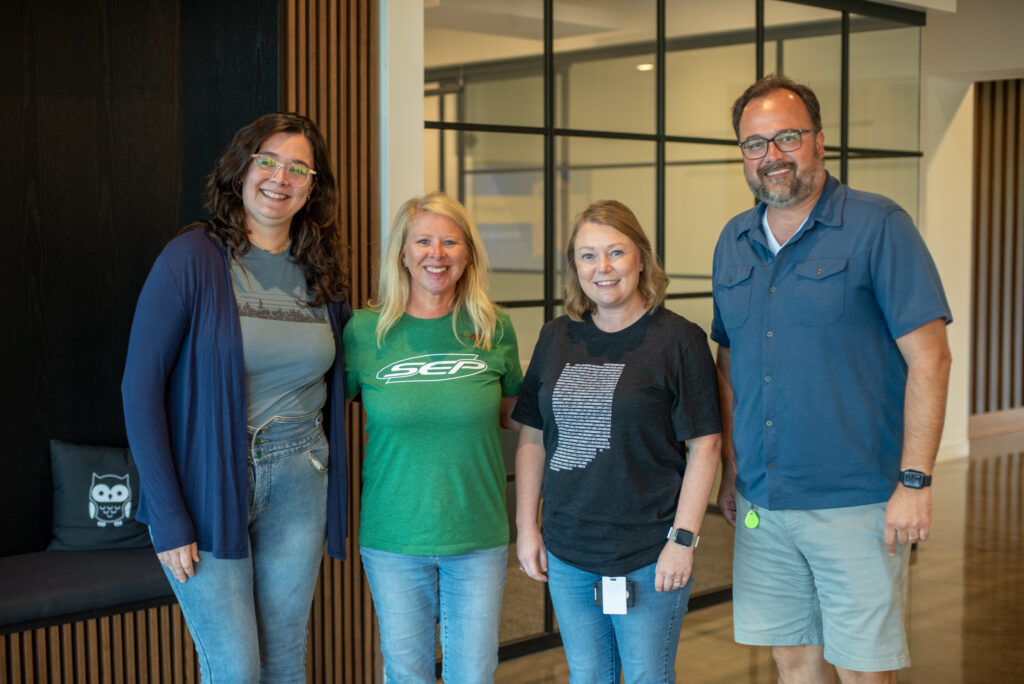 A group of SEPeers standing together decked out in SEP shirts in the SEP lobby.